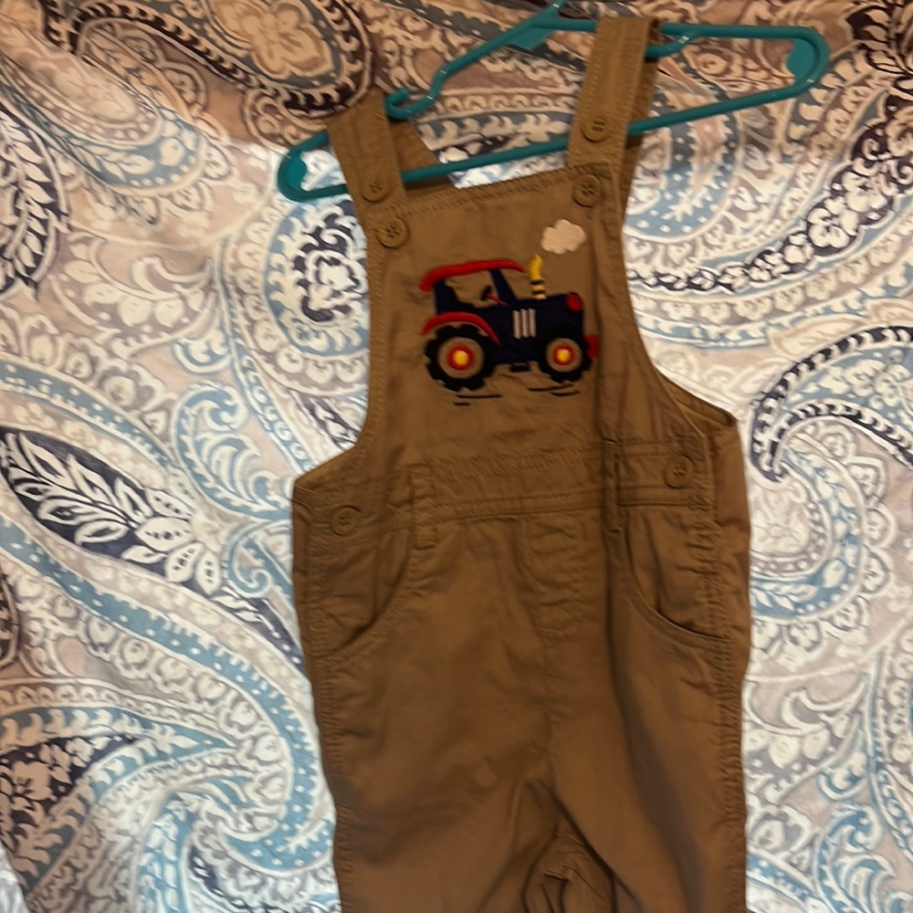 Khaki overalls with train embroidery on front pocket.